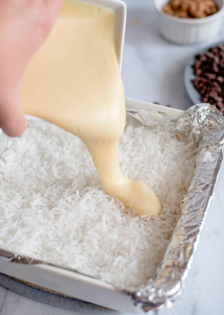 adding sweetened condensed milk on top of the coconut in the bars