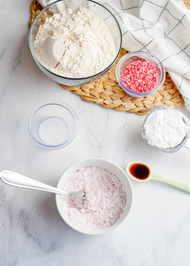 bowl of powdered sugar with the ingredients around it for the snowball cookies