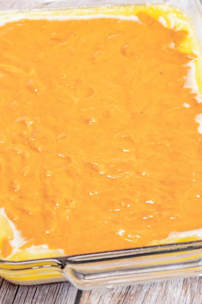 pumpkin batter on top of the cobbler topping batter in a baking dish