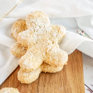 gingerbread dog treats on a cutting board with a white linen under the cookies