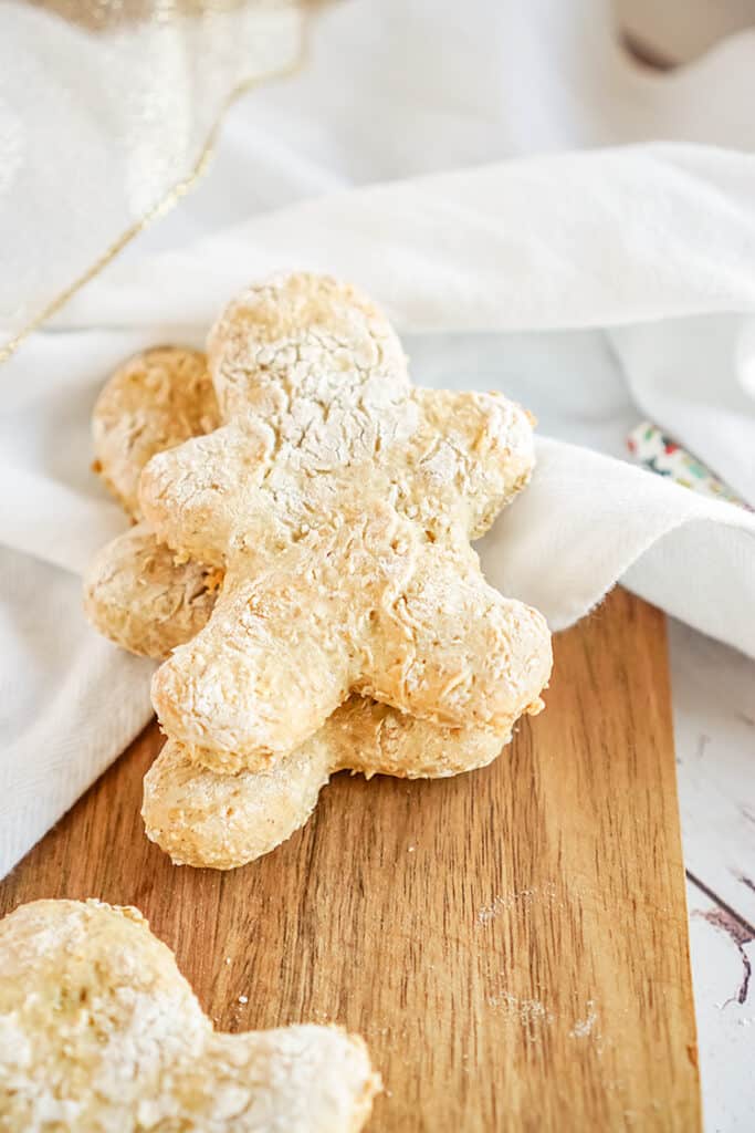 gingerbread dog treats on a cutting board with a white linen under the cookies