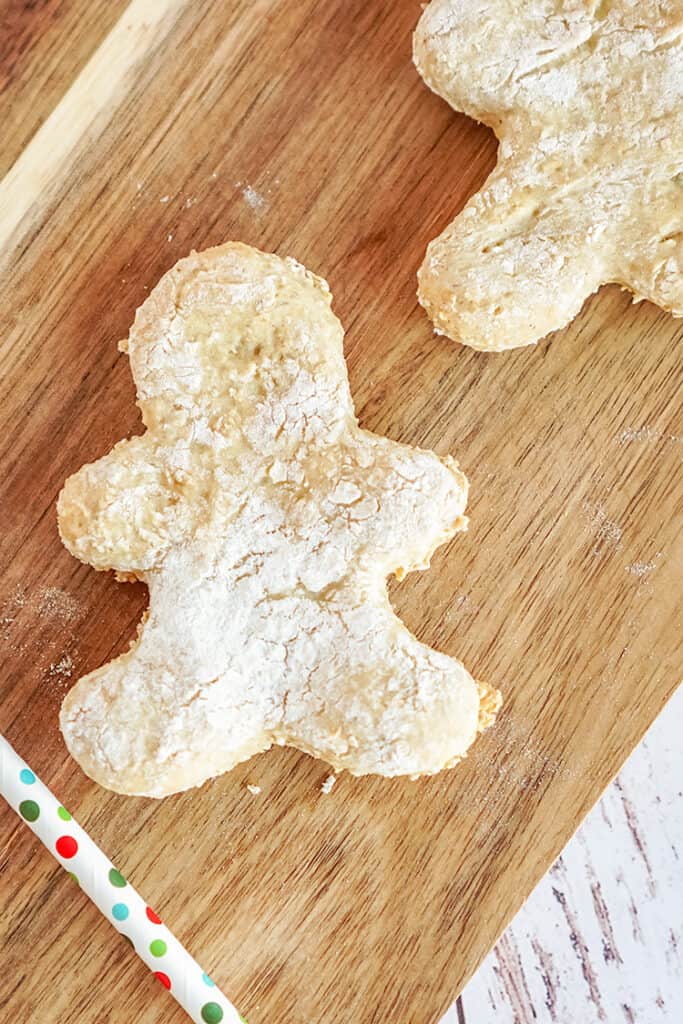 zoomed in photo of a gingerbread man dog treat on a wooden cutting board