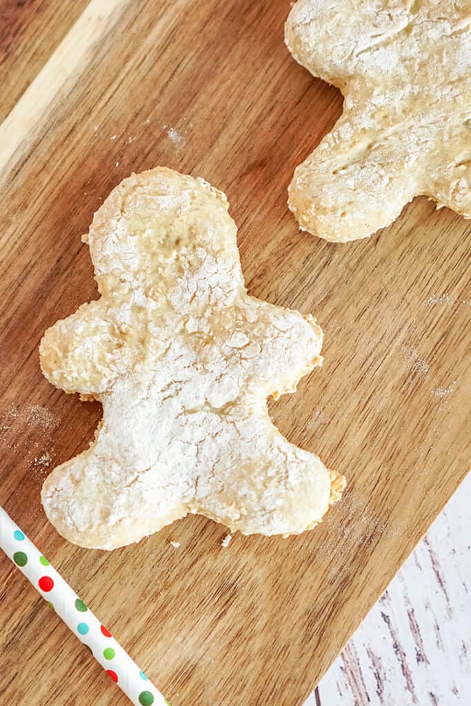 zoomed in photo of a gingerbread man dog treat on a wooden cutting board