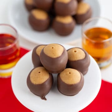 peanut butter balls on a white cupcake stand with a red fabric under the balls