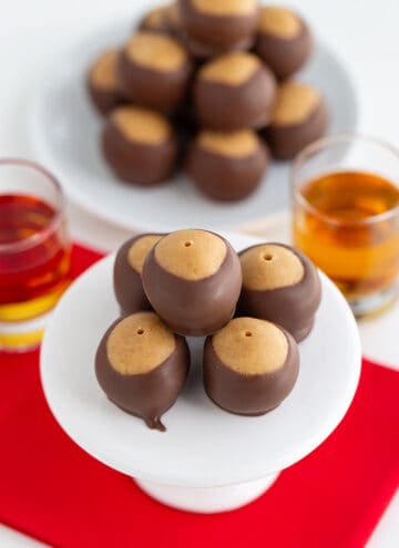 peanut butter balls on a white cupcake stand with a red fabric under the balls