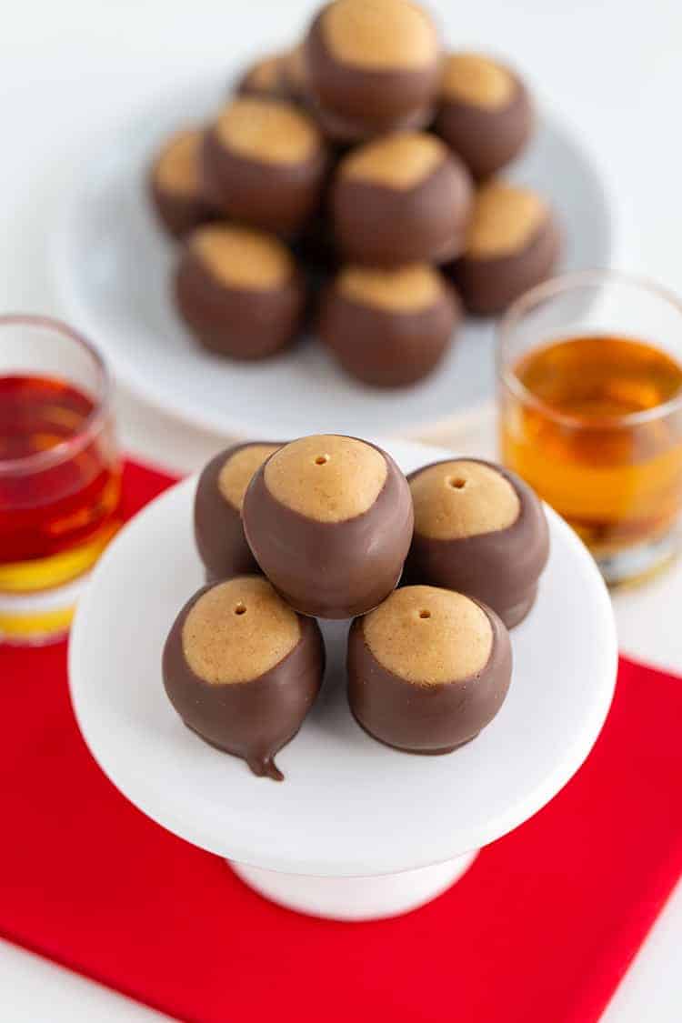 peanut butter balls on a white cupcake stand with a red fabric under the balls