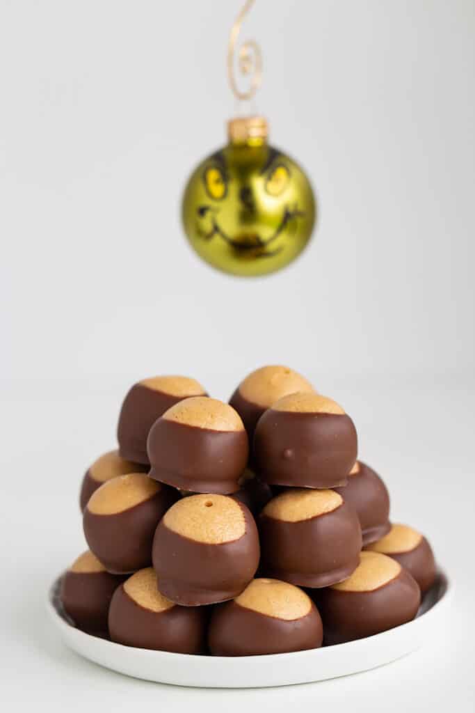 stack of peanut butter balls with a grinch ornament hanging behind it