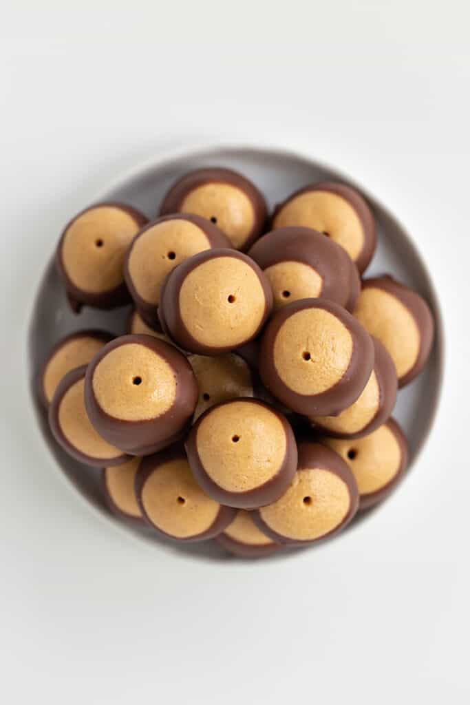 overhead photo of stacked buckeyes on a white plate on a white surface