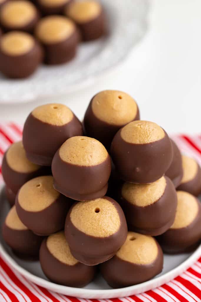 stack of buckeyes on a white plate with striped fabric under plate