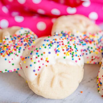 a cookie propped against other cookies with a pink linen behind them