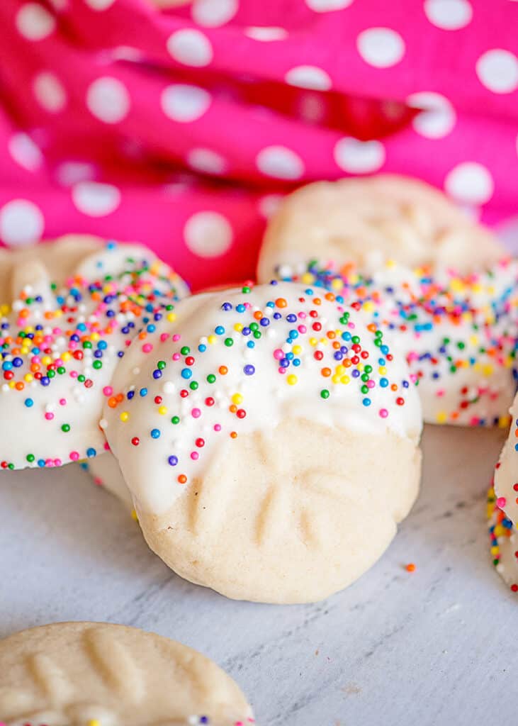 a cookie propped against other cookies with a pink linen behind them