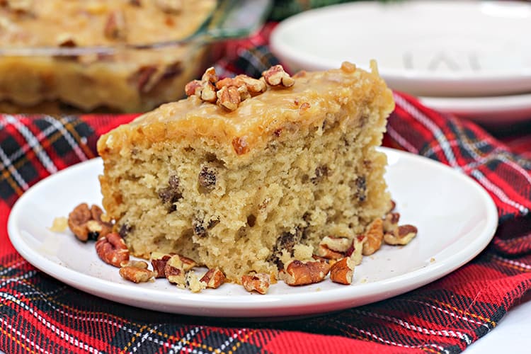 close up horizontal photo of the butter pecan cake on a white plate with plaid fabric under it