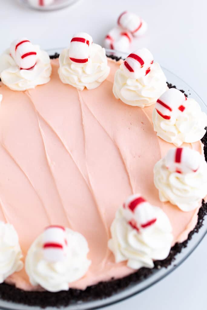 peppermint pie on a white surface with mints behind the pie