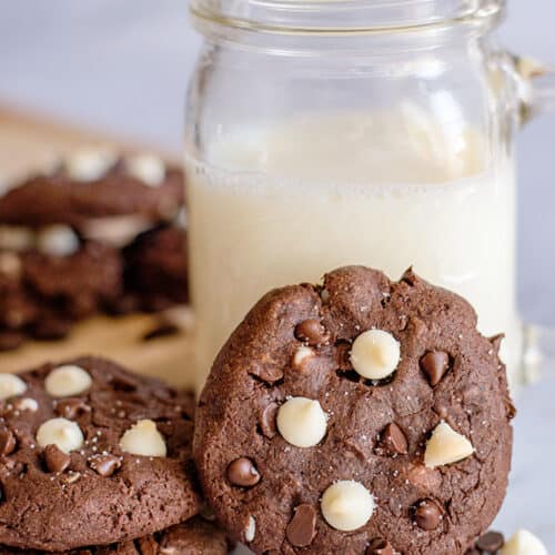 cookie propped up against a glass of milk on a marble background