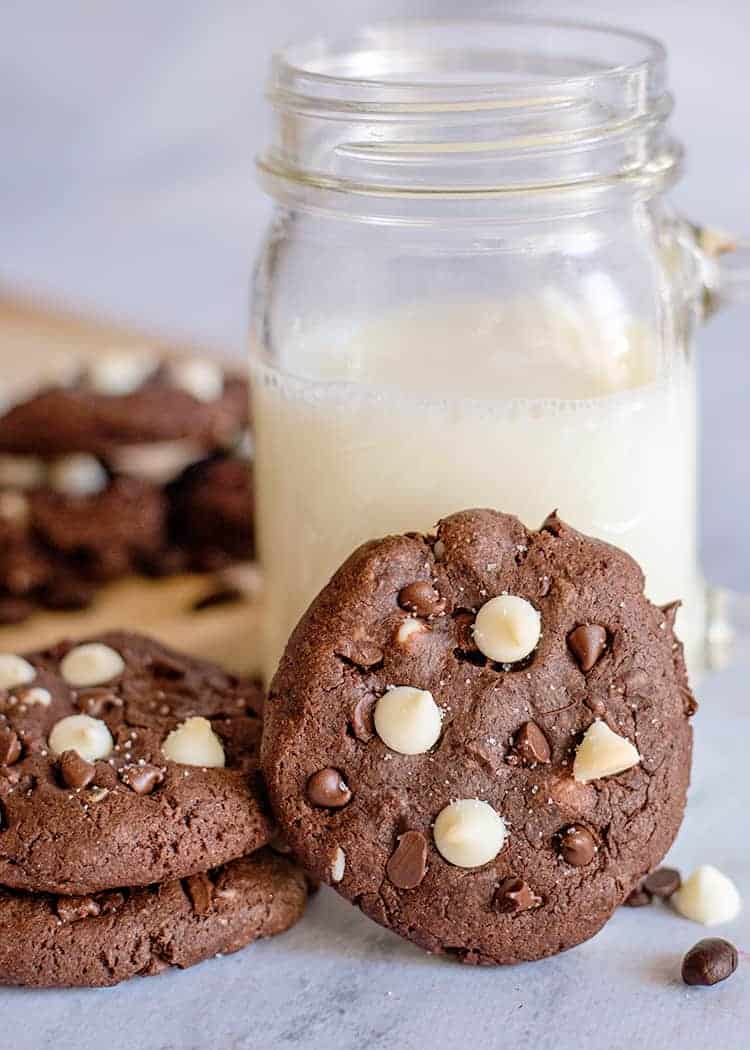 cookie propped up against a glass of milk on a marble background