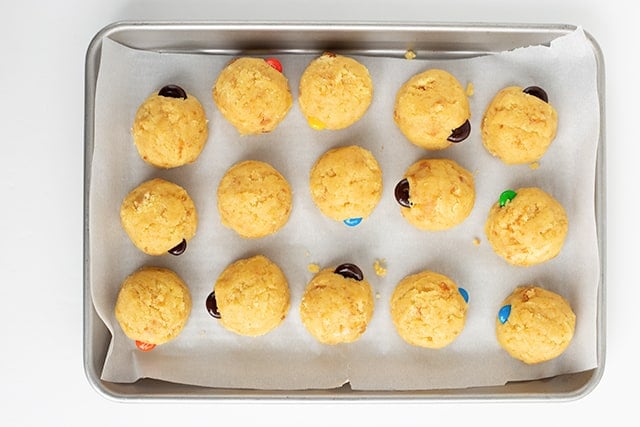 cake pop balls on a baking sheet with parchment paper under them