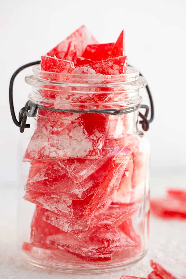 old timey mason jar full of red hard candy on a white background