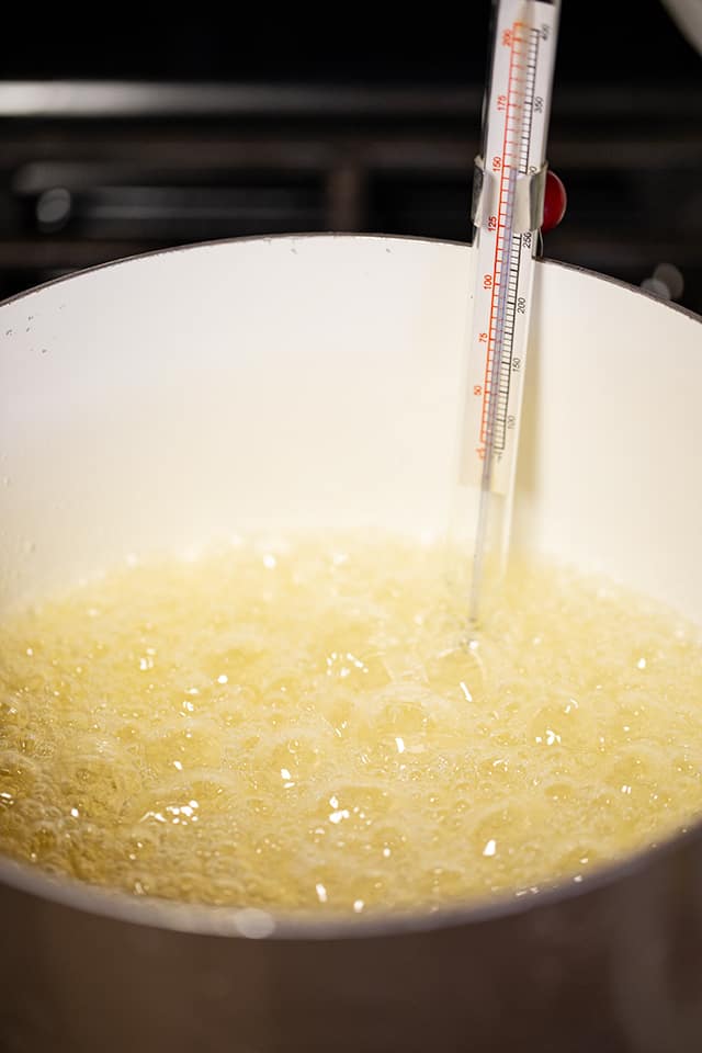 boiling sugar in a saucepan on the stove with a candy thermometer in it