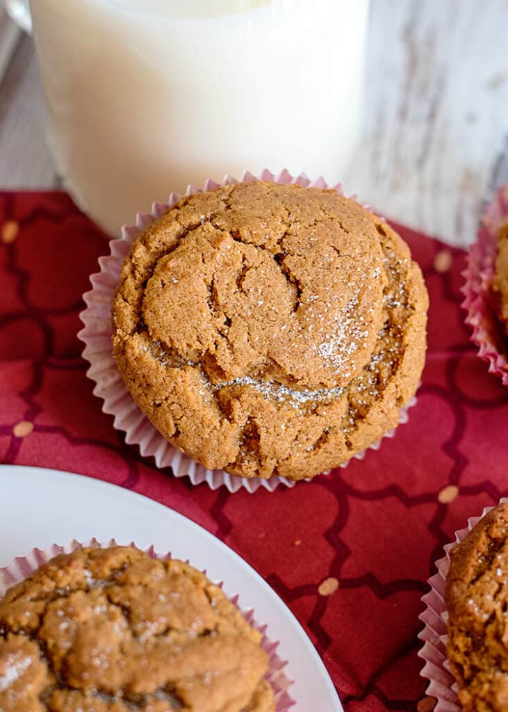 muffin propped up against a glass of milk and on top of a maroon fabric