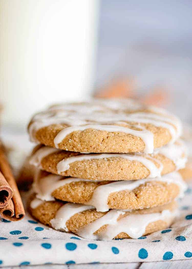 a shot of the side of a stack of cookies with a glass of milk behind it