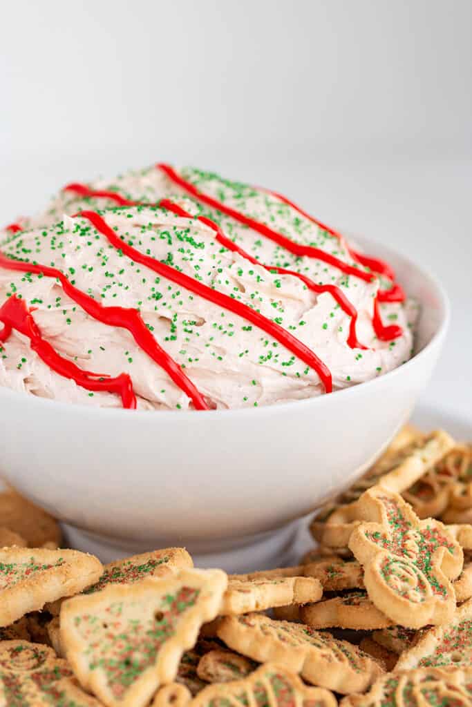 bowl of dip with holiday cookies around the dip and a white background