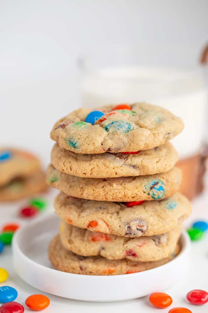 stack of cookies on a small white plate with a mug of milk behind it