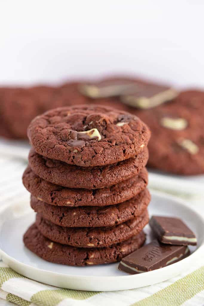 stack of chocolate cookies with andes mints beside the stack and a striped linen under the cookies