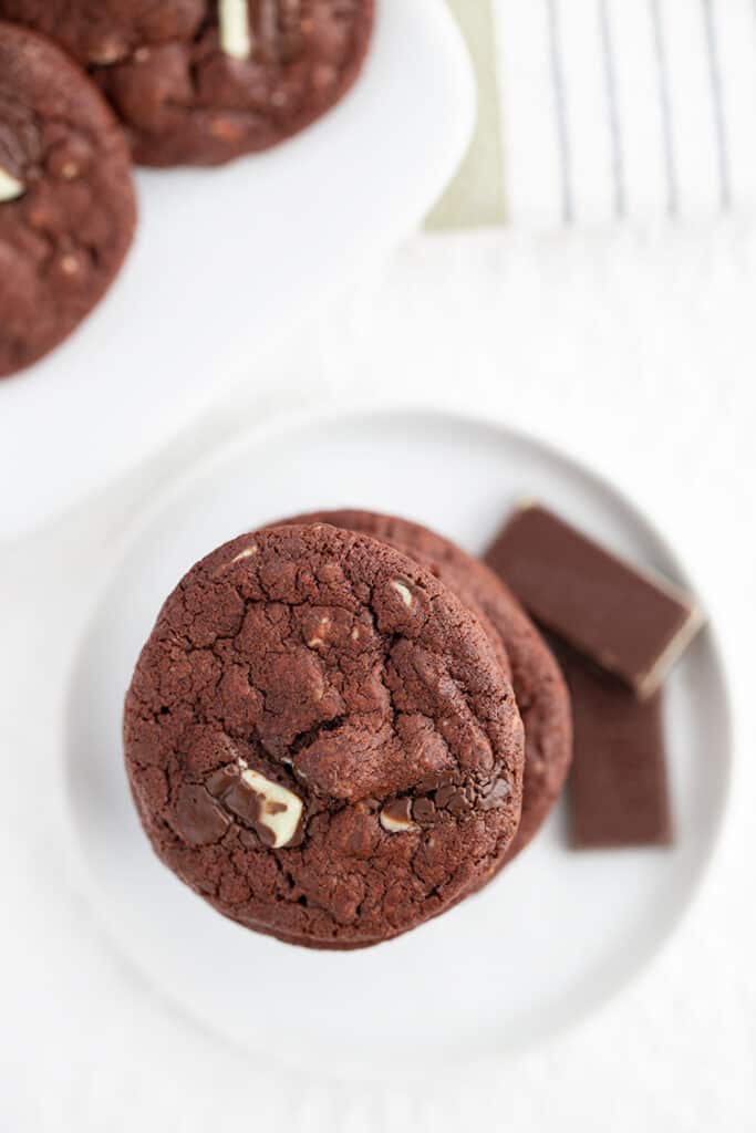 overhead photo of chocolate cookie with chocolate mints beside it on a white surface