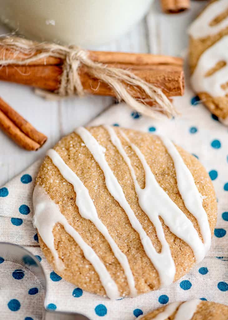 molasses cookie on a white and blue dotted linen with cinnamon sticks around it