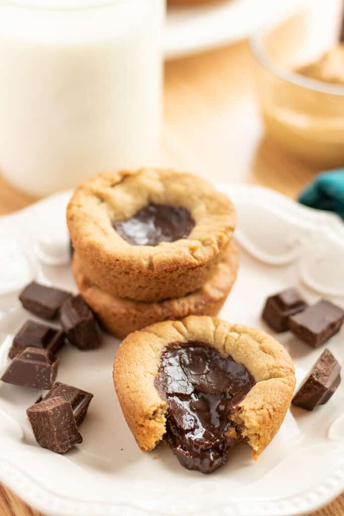 plate with a cookie cup on it with chocolate coming out of it and chocolate bites around it