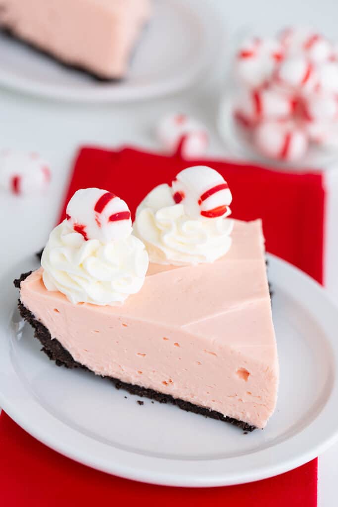 pie on a white dessert plate with a red fabric under the plate and mints behind the plate