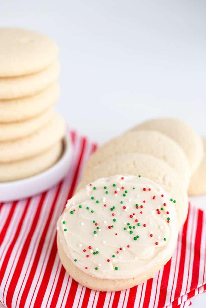cookies with holiday sprinkles on them sitting on a red and white plaid fabric