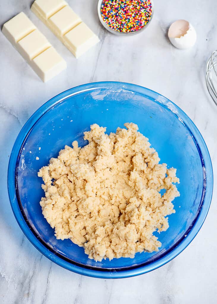 cookie dough in a blue mixing bowl with ingredients around it