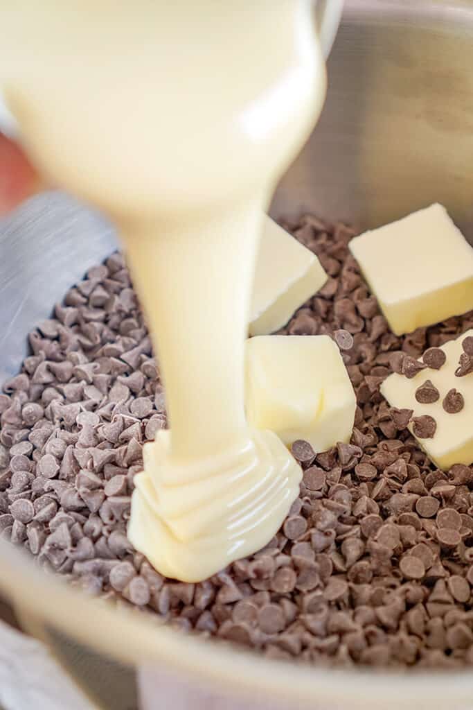 upclose photo adding the sweetened condensed milk to a bowl of chocolate chips and butter