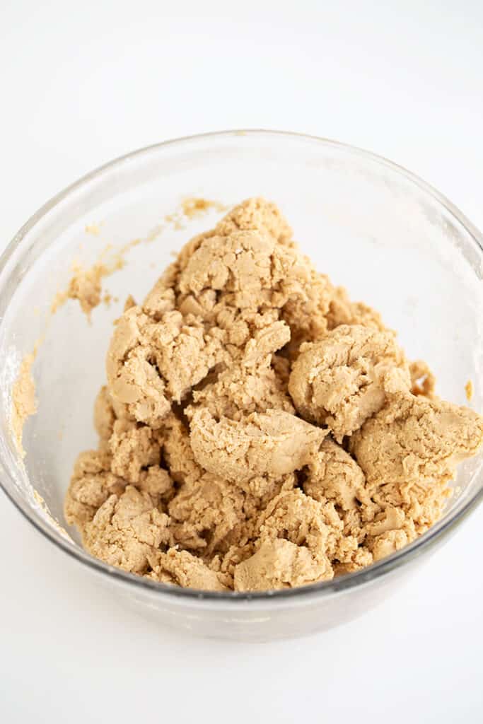 glass bowl full of peanut butter ball dough on a white surface