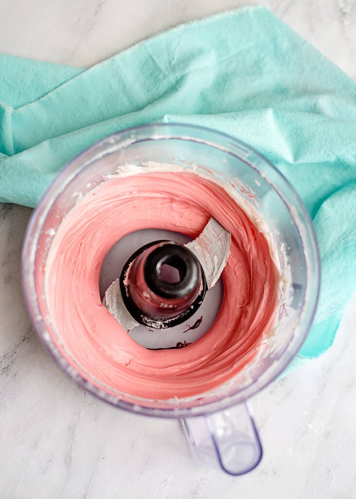 pink mint dough in a food processor bowl with a mint fabric under the bowl