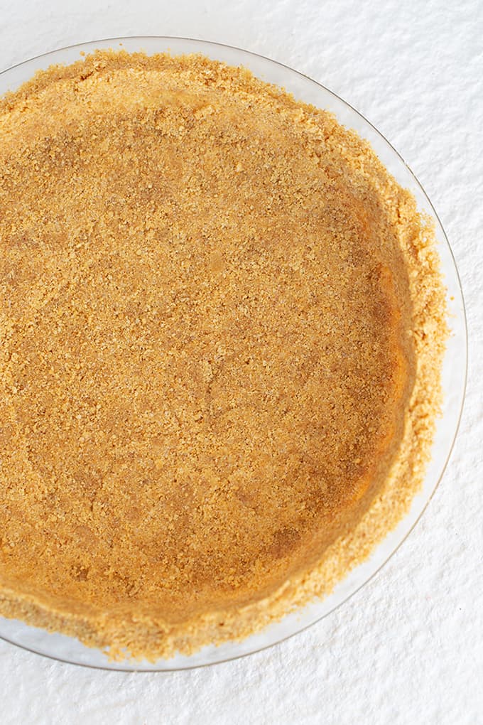 graham cracker crust in a glass pie plate on a white background