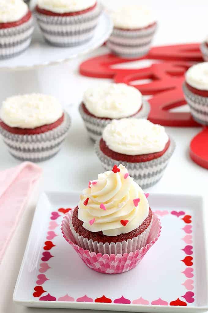 a cupcake on a square plate with hearts on it