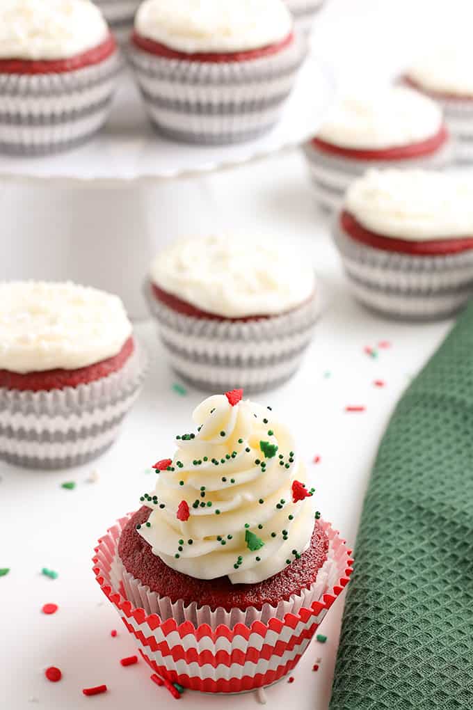 Christmas decorated cupcake with festive sprinkles on a white background with a green linen beside the cupcake