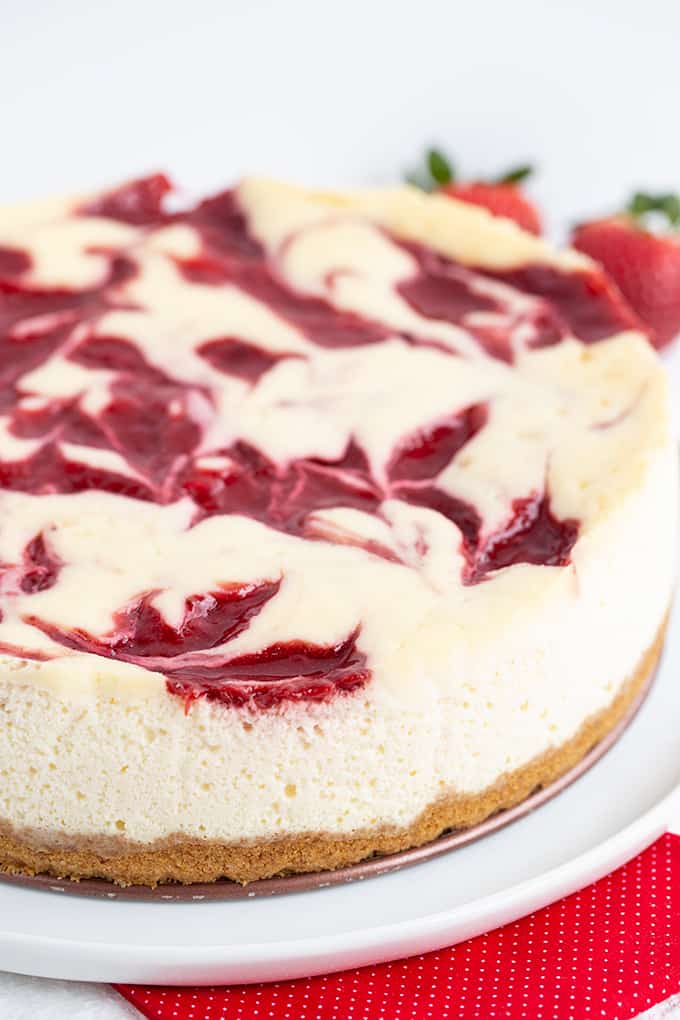 Photo showing the side and top of the cheesecake while it's sitting on a white plate with a red fabric under it