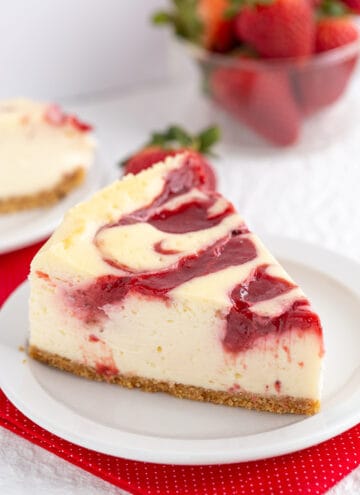 a slice of cheesecake with a strawberry swirl on top on a small white plate