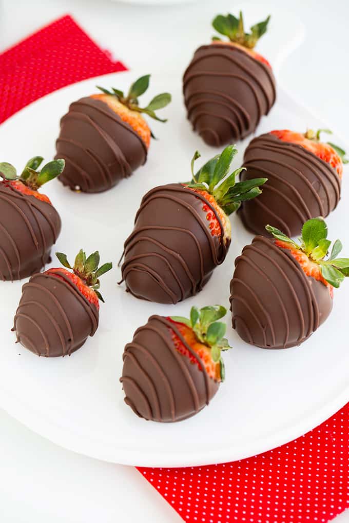 overhead photo showing the chocolate covered strawberries in the center of the platter with a red fabric
