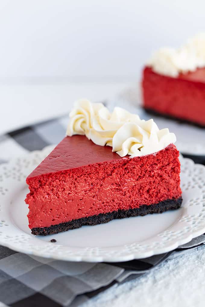 slice of cheesecake on a small white plate with a black and white linen under it