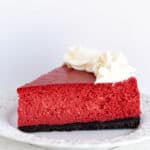 slice of red cheesecake on a white plate on a white background
