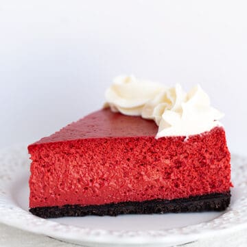 slice of red cheesecake on a white plate on a white background