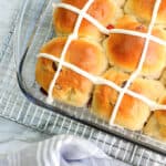 hot cross buns in a baking dish with a wire rack and linen under it