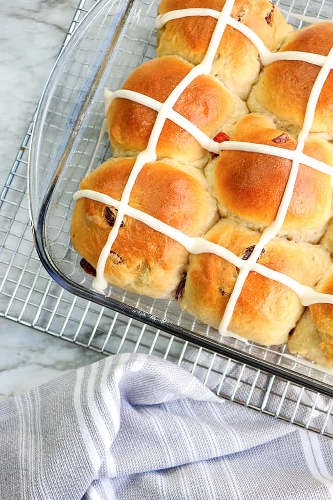 hot cross buns in a baking dish with a wire rack and linen under it