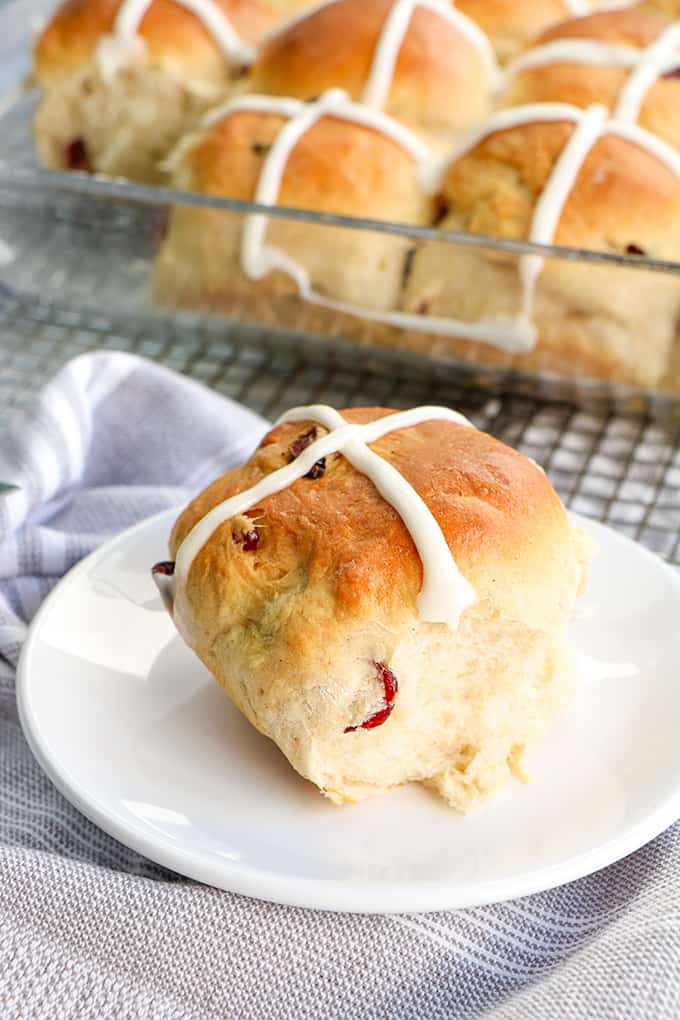 a small white plate with a hot cross bun on it on a gray fabric