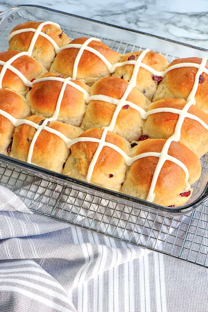 a pan full of hot cross buns with a gray striped fabric
