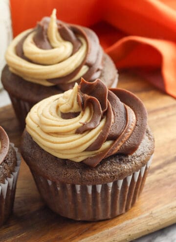 a chocolate cupcake on a cutting board with orange linen behind it